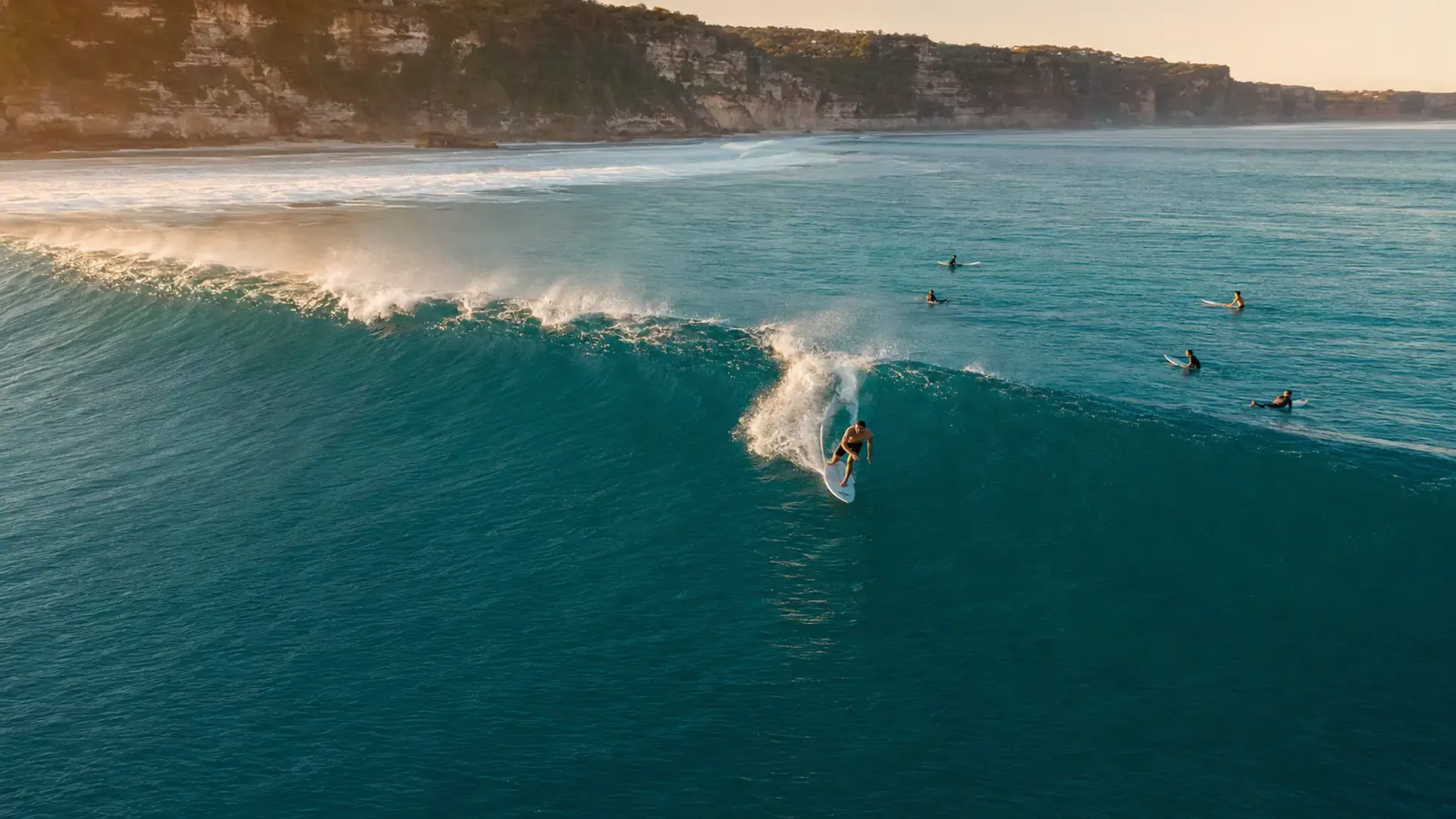 Surfer drawing a line across an Uluwatu wave at dawn